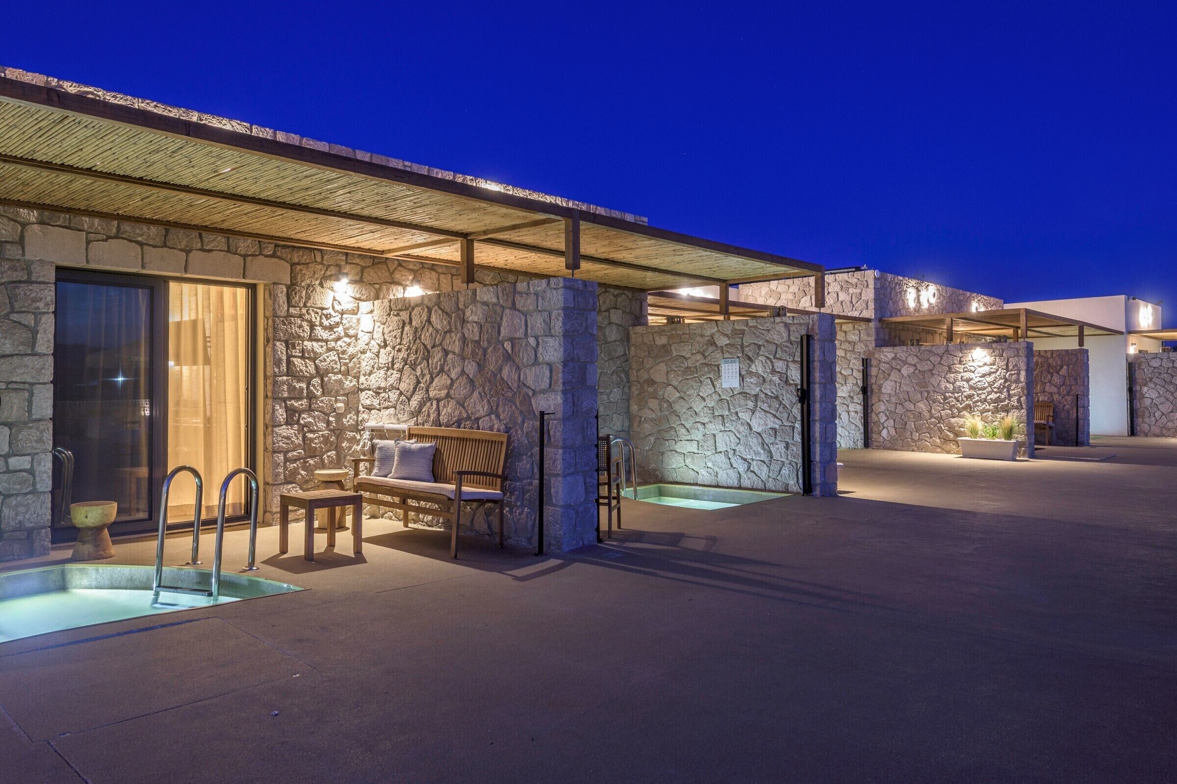 A stone building with a pool, outdoor seating, and a covered patio area.