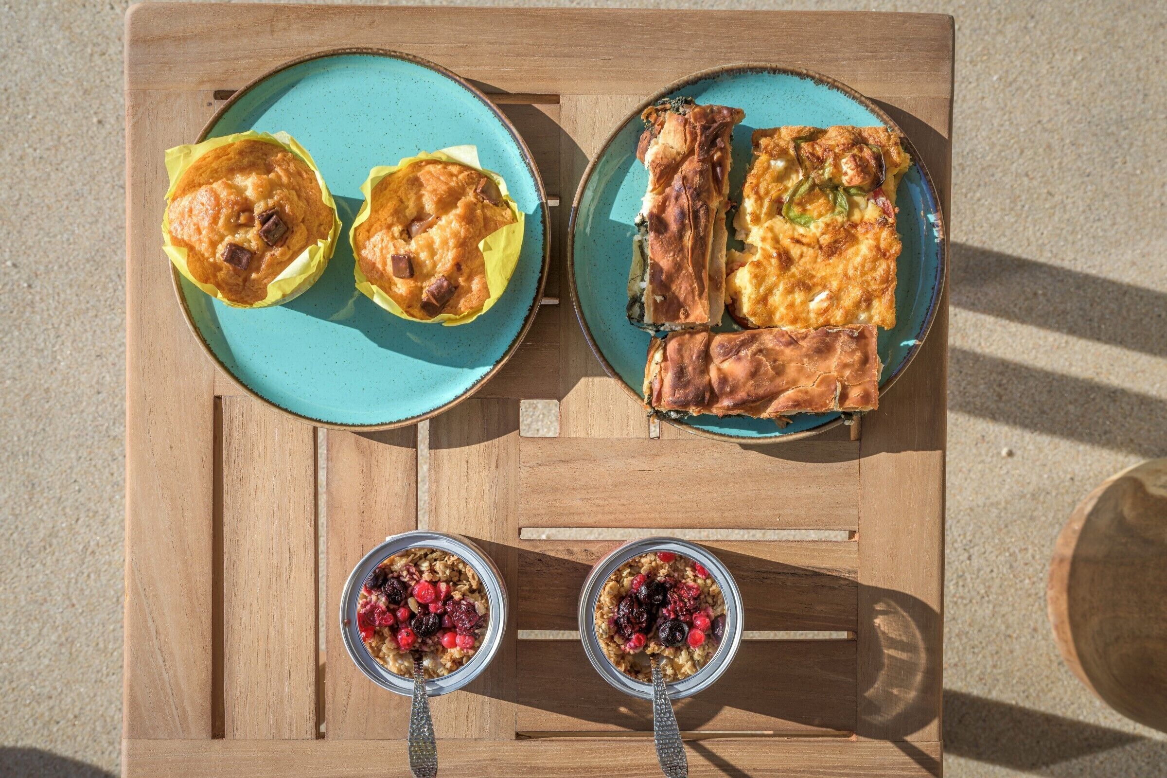 Una mesa de madera con dos platos de muffins y dos tazones de cereal.
