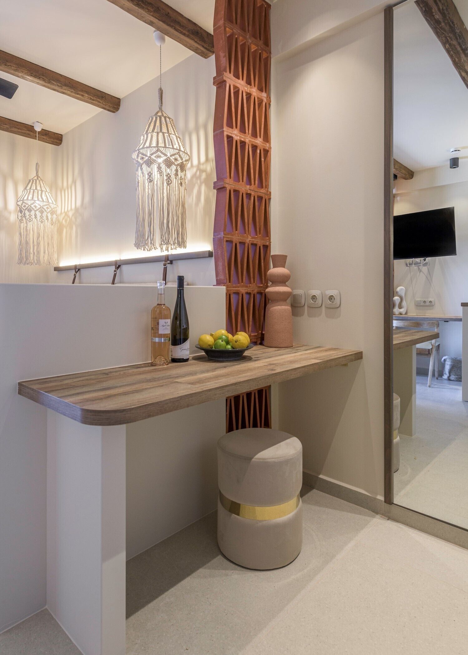 Une cuisine moderne avec des poutres en bois, des luminaires suspendus, un meuble-bar intégré et un petit tabouret.