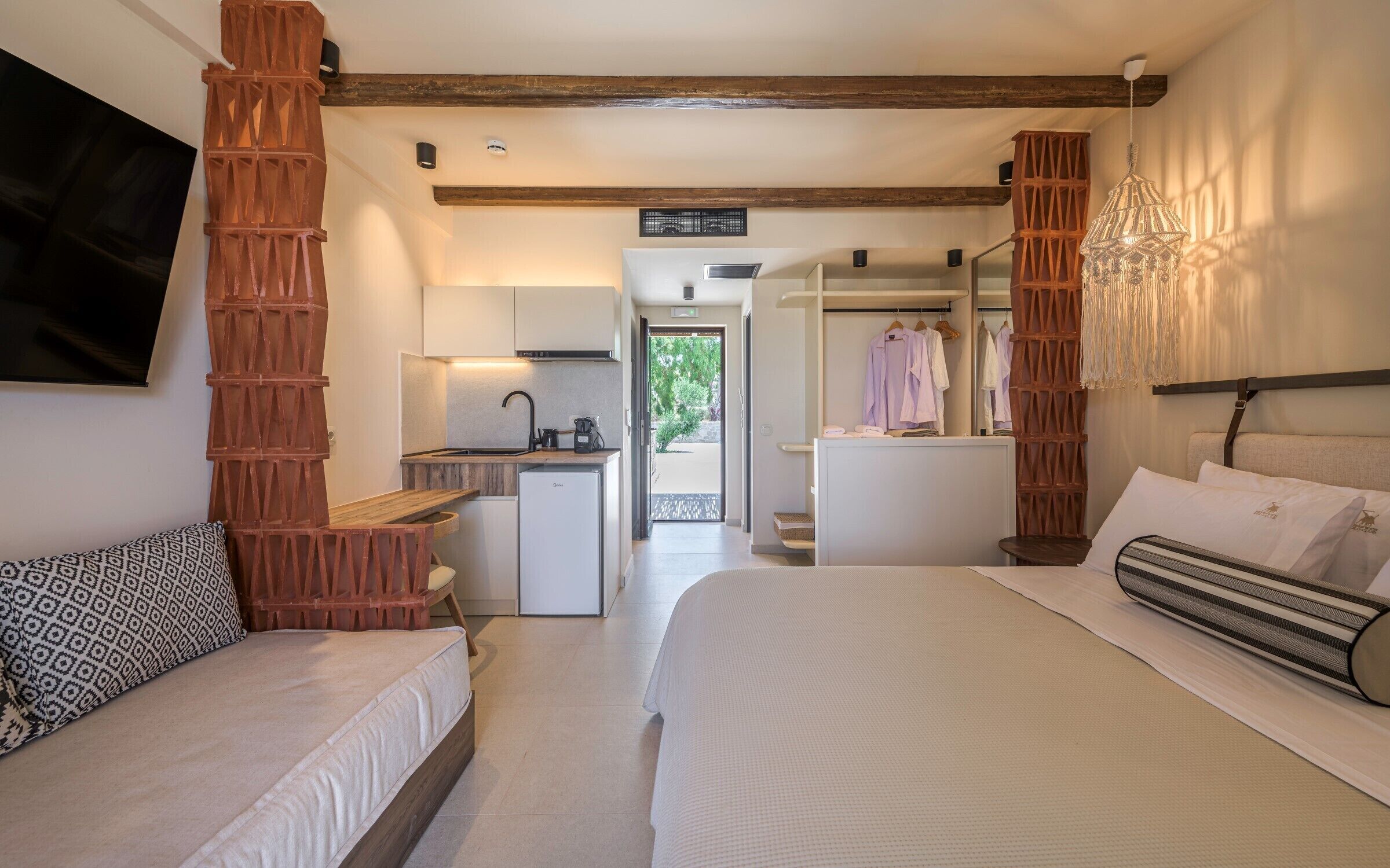 Habitación de hotel con dos camas, kitchenette, baño y vistas al exterior.