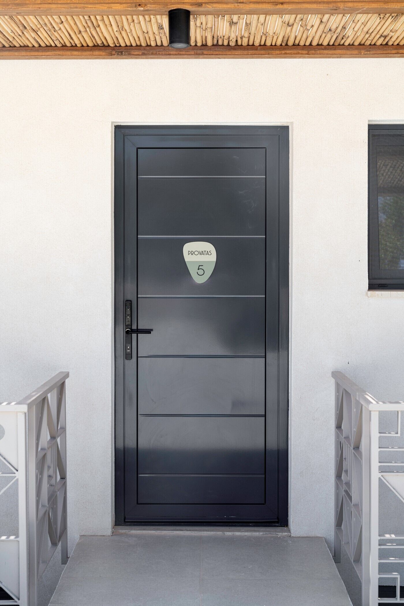 Una puerta negra moderna con un letrero que dice 'PROVINTAS 5' y un picaporte de metal.