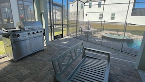 A patio with a grill, a bench, and a view of a house and swimming pool. - 8957-HiltonRidge (Kissimmee)