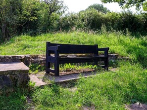 Een zwarte bank in een grasveld met stenen trappen erheen.