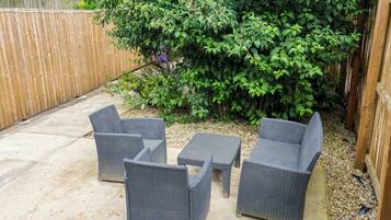 A patio area with wicker furniture, a concrete floor, and a wooden fence.