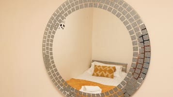 Ein runder Spiegel mit Mosaikbordüre an einer Wand.