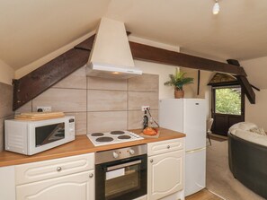 Een kleine keuken met een magnetron, fornuis, oven en een witte koelkast.