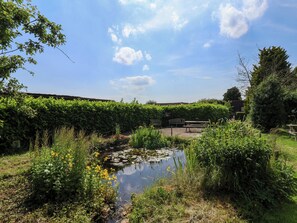 Un jardí tranquil amb un estany, bancs i vegetació exuberanta.