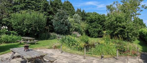Une table de pique-nique dans un jardin, avec un chemin en pierre.