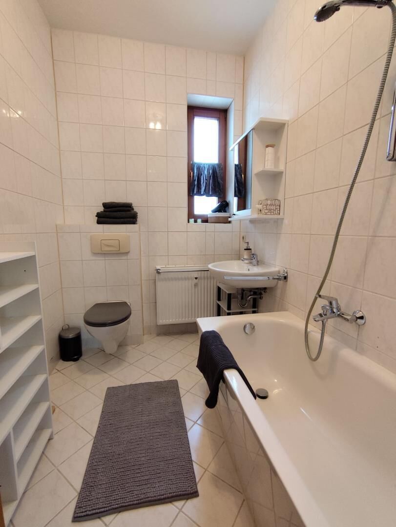 A bathroom with a bathtub, toilet, sink, and a small window.