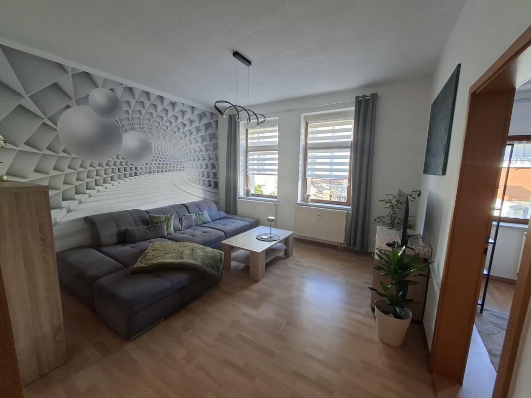 A modern living room with a sectional sofa, a coffee table, and a decorative wall with geometric patterns.
