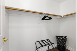 A closet with a wooden rod, a black hanger, and a black chair. - Fairway Oasis • Private Pool, Spa & Putting Green (Chandler)