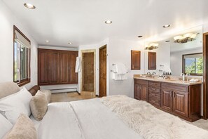 Ein Schlafzimmer mit einem großen Bett, ein Badezimmer mit Holzschränken, einer Dusche und einem Waschtisch.