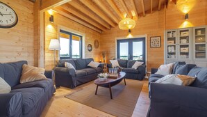 Ein gemütliches Blockhaus-Interieur mit zwei Sofas, einem Couchtisch und einem Bücherregal.