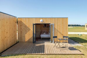 A wooden cabin with a bed, a table, and a chair outside. - Les Lodges d'Opale, 32 guests, 16 rooms (Vironchaux)