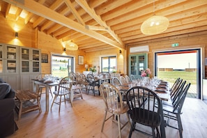 A dining area with wooden tables and chairs, a view of the outdoors through large windows, and a wooden ceiling structure. - Les Lodges d'Opale, 32 guests, 16 rooms (Vironchaux)
