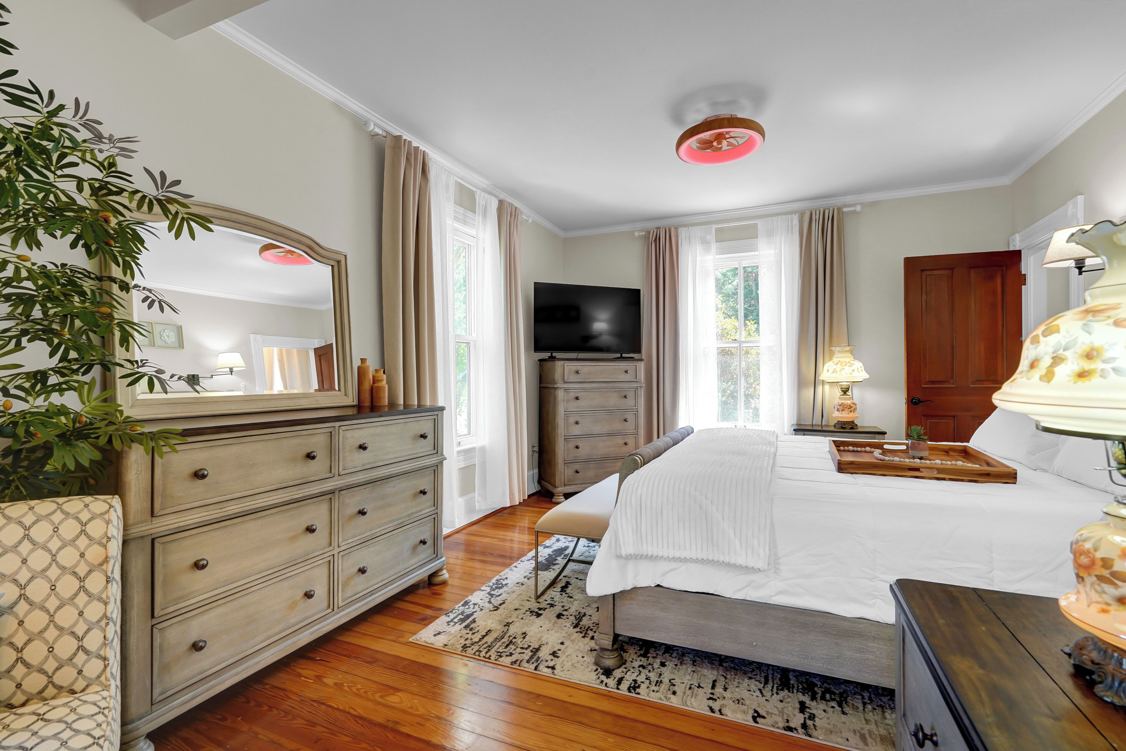 Une chambre à coucher avec un lit, une commode, une télévision et une plante.