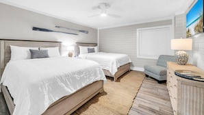 A bedroom with two beds, a ceiling fan, a large window, and a wall-mounted TV. - Watercrest 1006 (Panama City Beach)