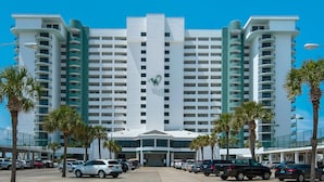 A large, multi-story hotel with a prominent 'W' logo on the facade, featuring a central entrance and a parking lot with several cars. - Watercrest 1006 (Panama City Beach)