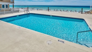 Une piscine d’un bleu éclatant, agrémentée d’un panneau indiquant « INTERDIT DE PLONGER », d’une clôture blanche et offrant une vue sur l’océan.
