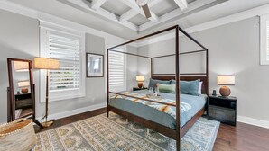 Un letto a baldacchino con un tappeto decorato, comodini con lampade e una ventola a soffitto.