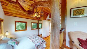A wooden interior with a bed, a chair, a ceiling fan, and a window. - Luxury Treehouse, gas fireplace, BBQ, firepit, outdoor dining, shared creek access (Weaverville)