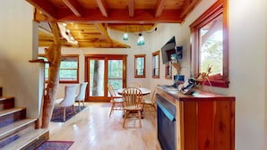 A wooden interior with a dining area, kitchen, and large windows. - Luxury Treehouse, gas fireplace, BBQ, firepit, outdoor dining, shared creek access (Weaverville)