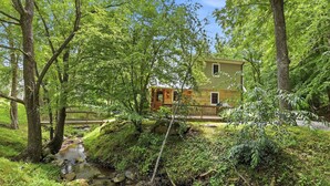 A house surrounded by lush greenery and a small stream. - Creekfront Cottage, scenic views, dog-friendly, firepit, gas grill, gas fireplace (Weaverville)