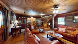 Ein gemütliches Blockhaus-Interieur mit Essbereich, Ledersofas, einer Treppe und einer Küche.