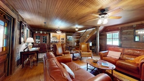 Ein gemütliches Blockhaus-Interieur mit Essbereich, Ledersofas, einer Treppe und einer Küche.