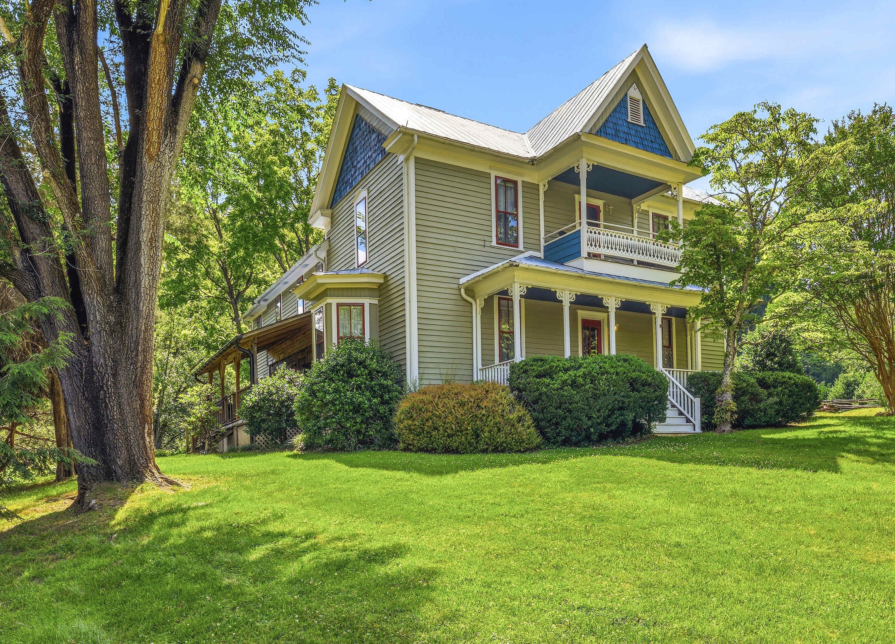 A two-story house with a porch, surrounded by trees and a well-maintained lawn.