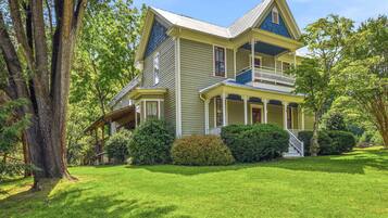 A two-story house with a porch, surrounded by trees and a well-maintained lawn.