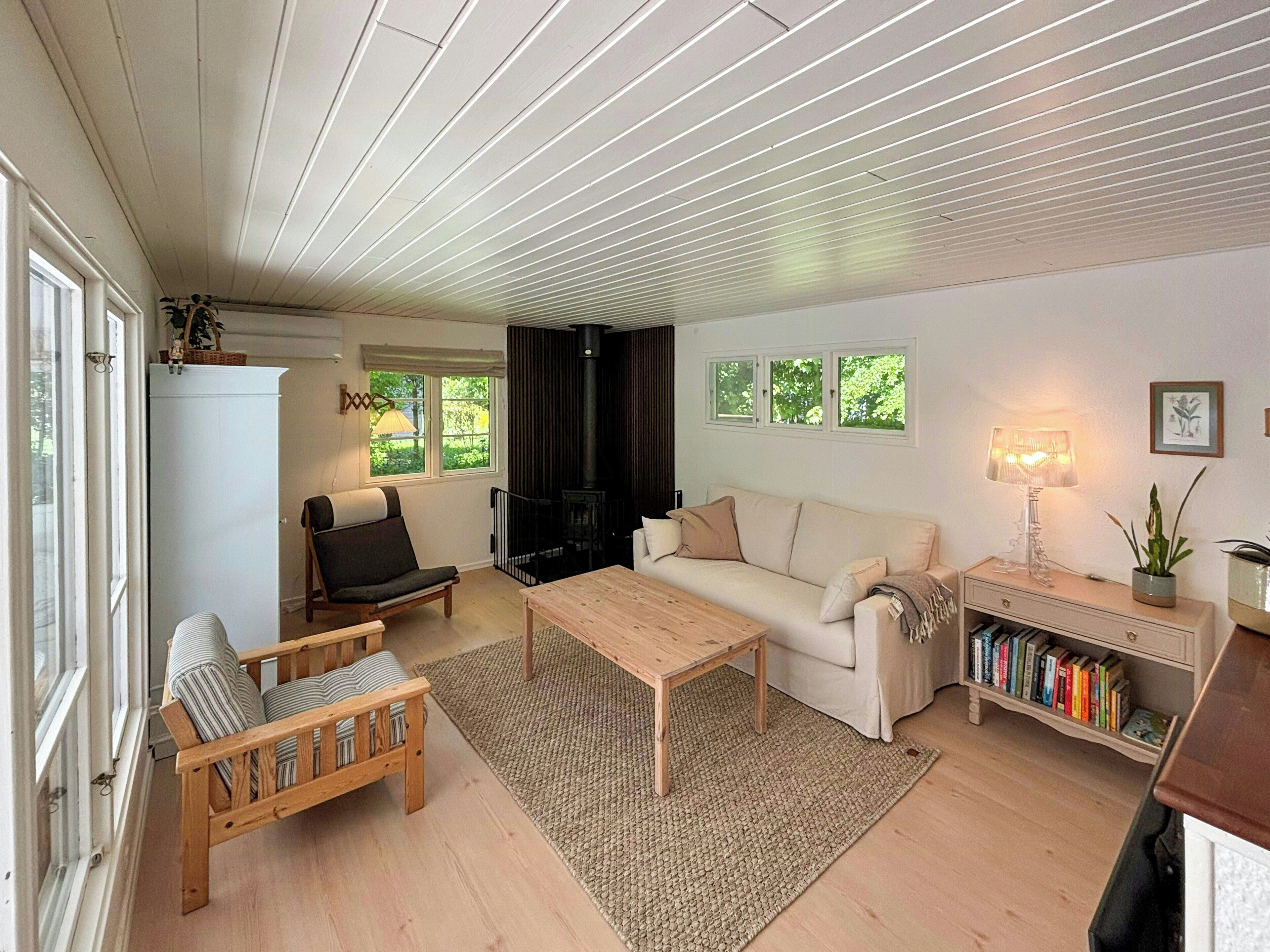 En hyggelig stue med sofa, lænestol, sofabord og reol.