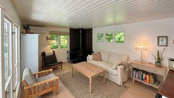 En hyggelig stue med sofa, lænestol, sofabord og reol.