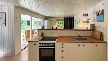 A modern kitchen with a central island, a built-in oven, and a large window.