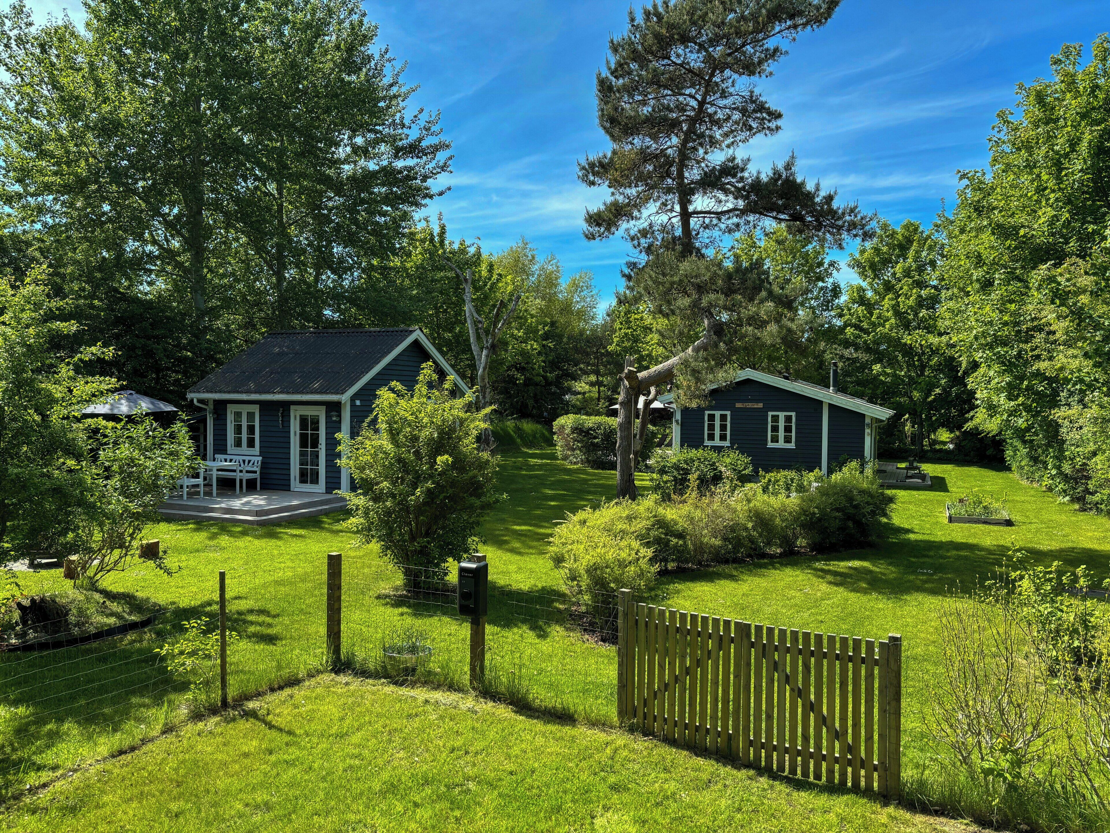 A small, dark-colored house with a porch and a fenced yard.