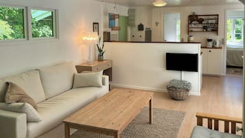 A living room with a sofa, coffee table, and a TV mounted on the wall.