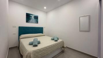Ein Schlafzimmer mit Bett, einem Kopfteil, einem Wandbild und einem Schminkspiegel am Nachttisch.