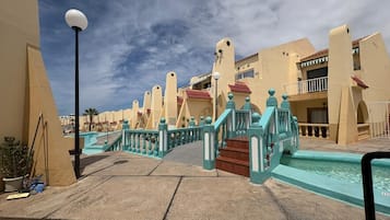 Ein Resort mit Pool, türkis gestrichenen Geländern und blauem Himmel.