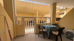 Un patio con mesa y sillas, una reja y un equipo de aire acondicionado.