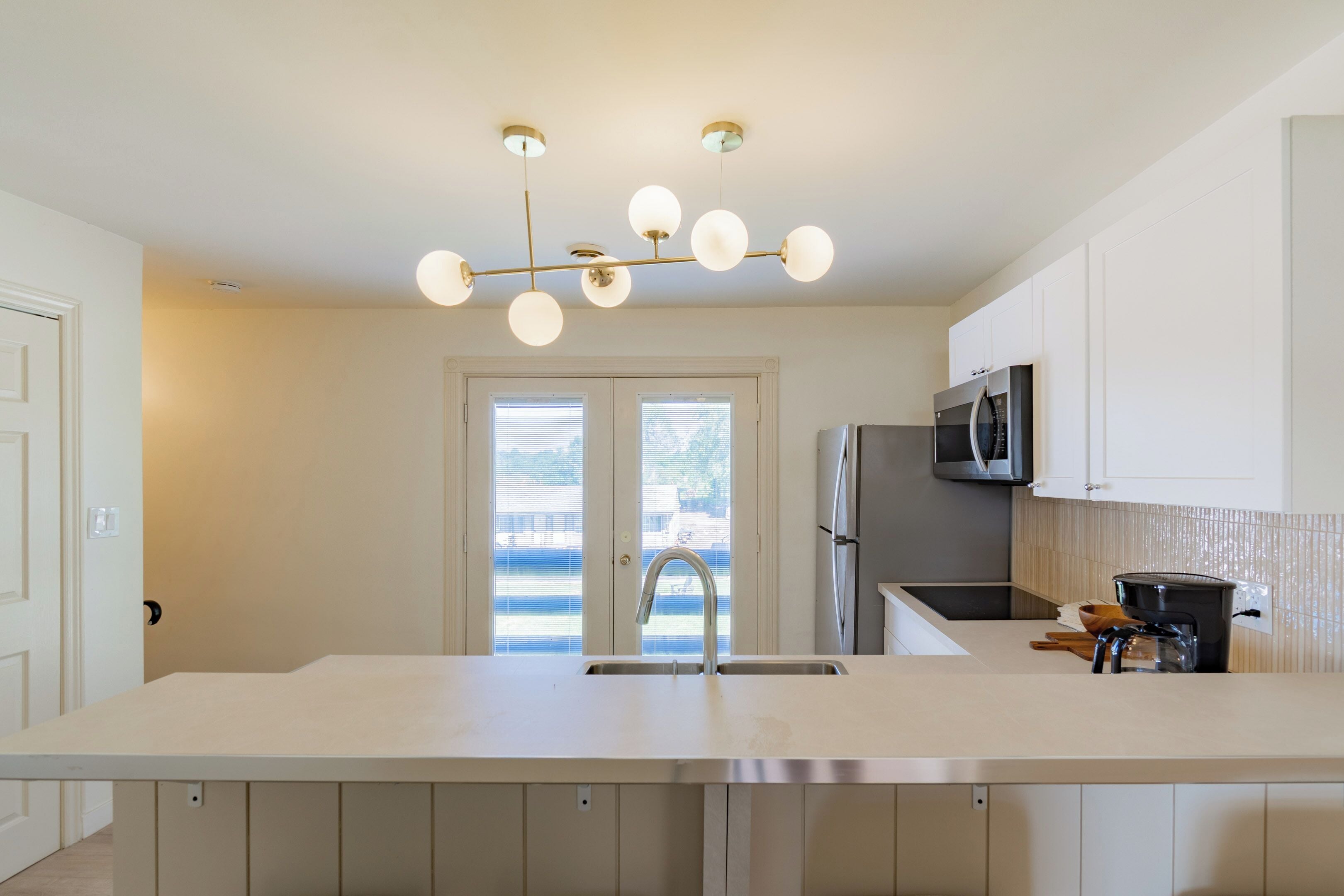 Una cocina moderna con una isla central, electrodomésticos de acero inoxidable y una lámpara colgante.