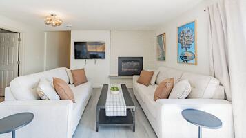 A modern living room with two sofas, a coffee table, a TV, and a fireplace.