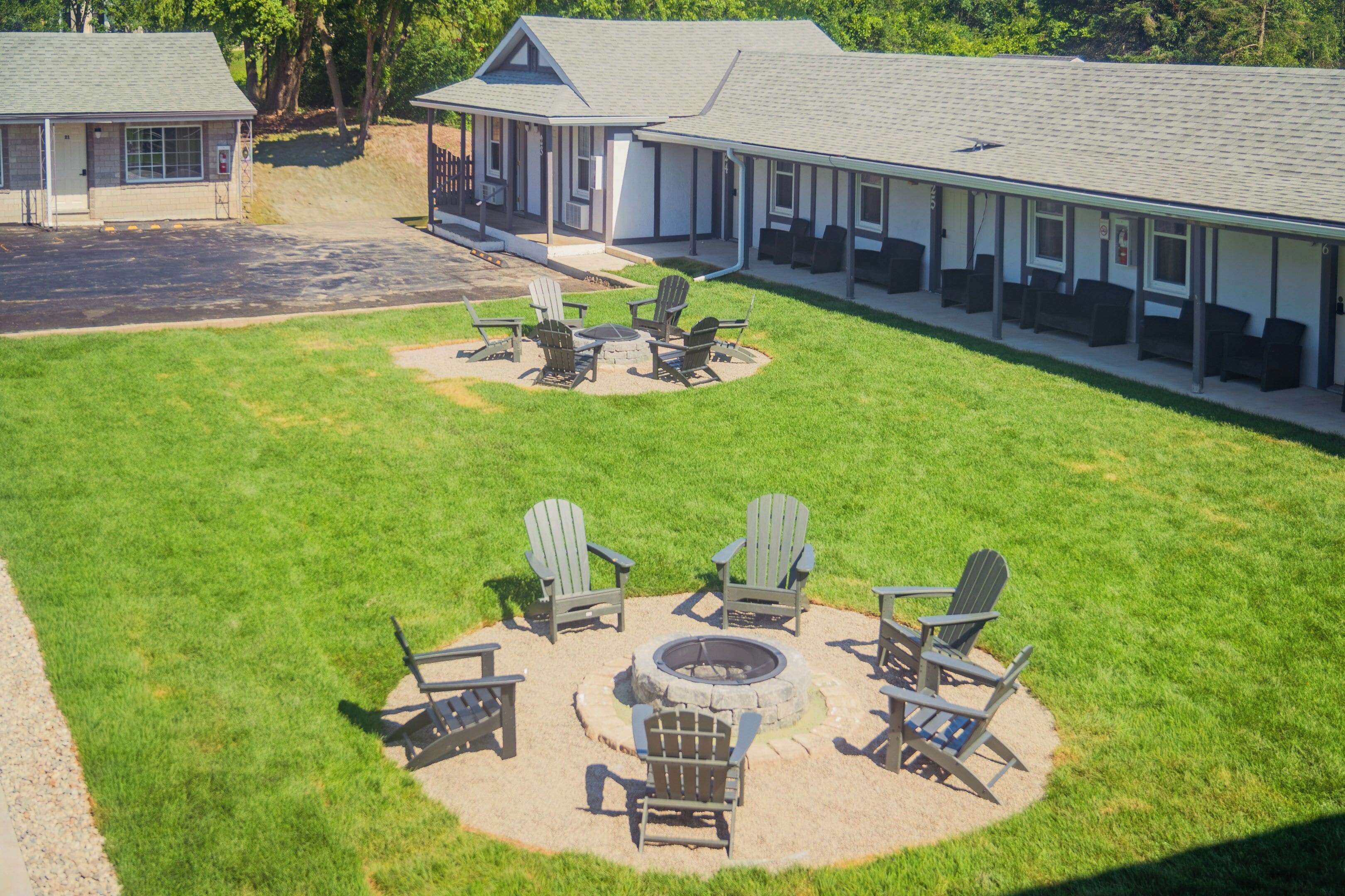 A building with a covered outdoor seating area with Adirondack chairs and a fire pit.