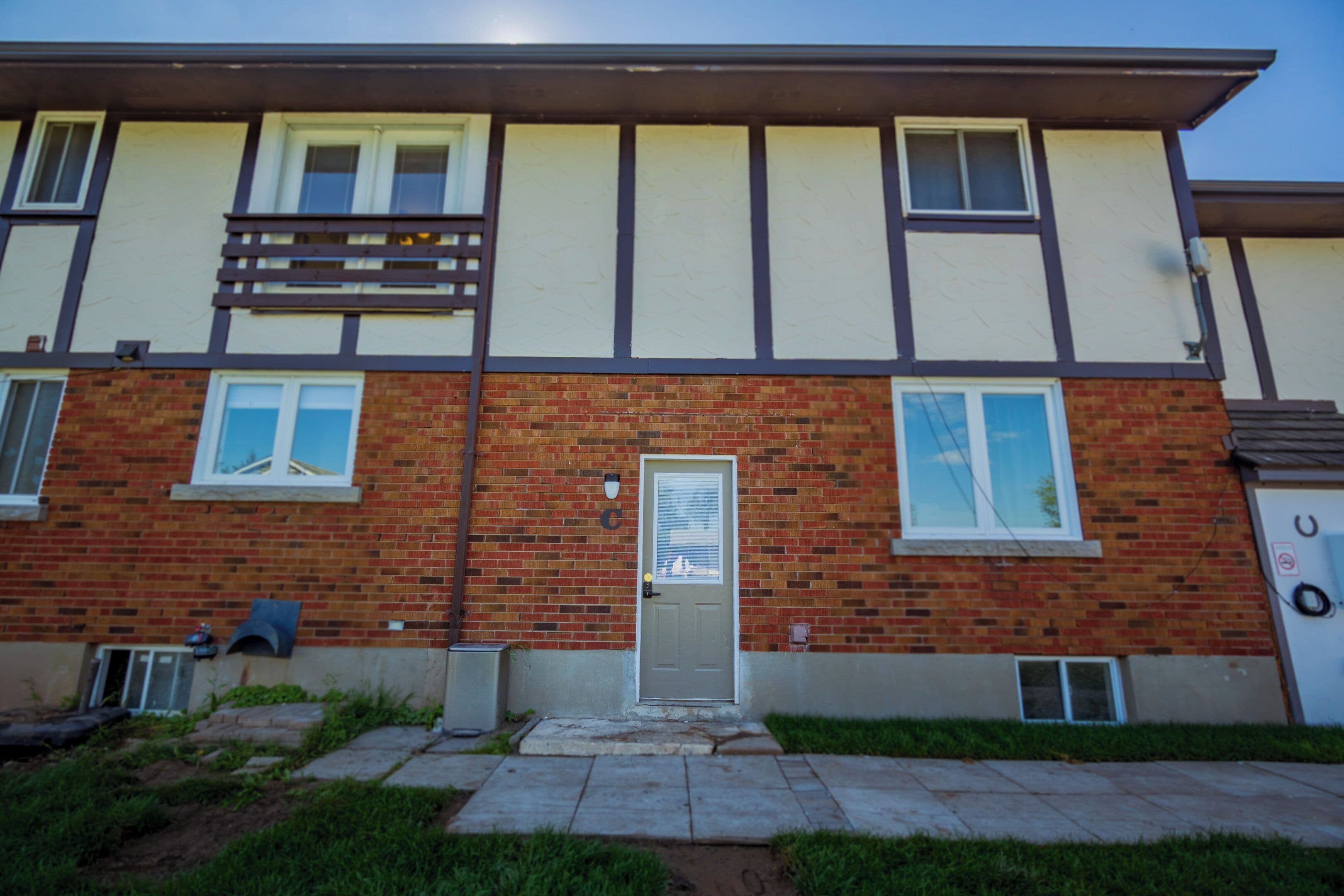 A two-story building with a brick facade, a front door, and a small overhang above the door.