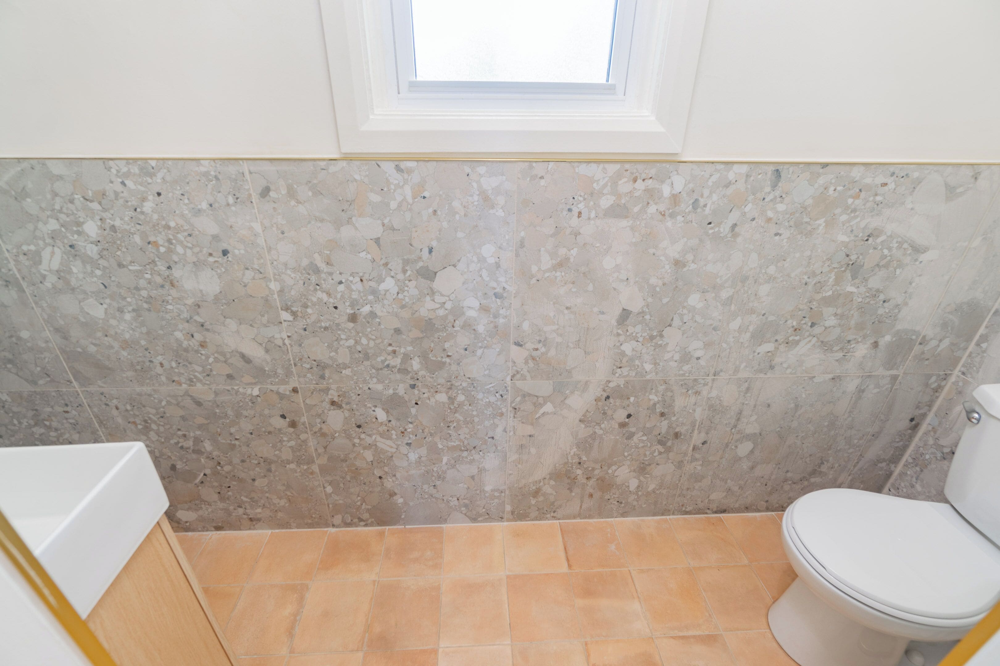 Un bagno con un WC bianco, una vasca da bagno e un pavimento in terrazzo.