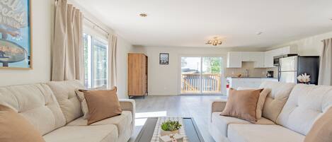 A spacious living room with a sofa set, a coffee table with a plant, and a view to the outside.