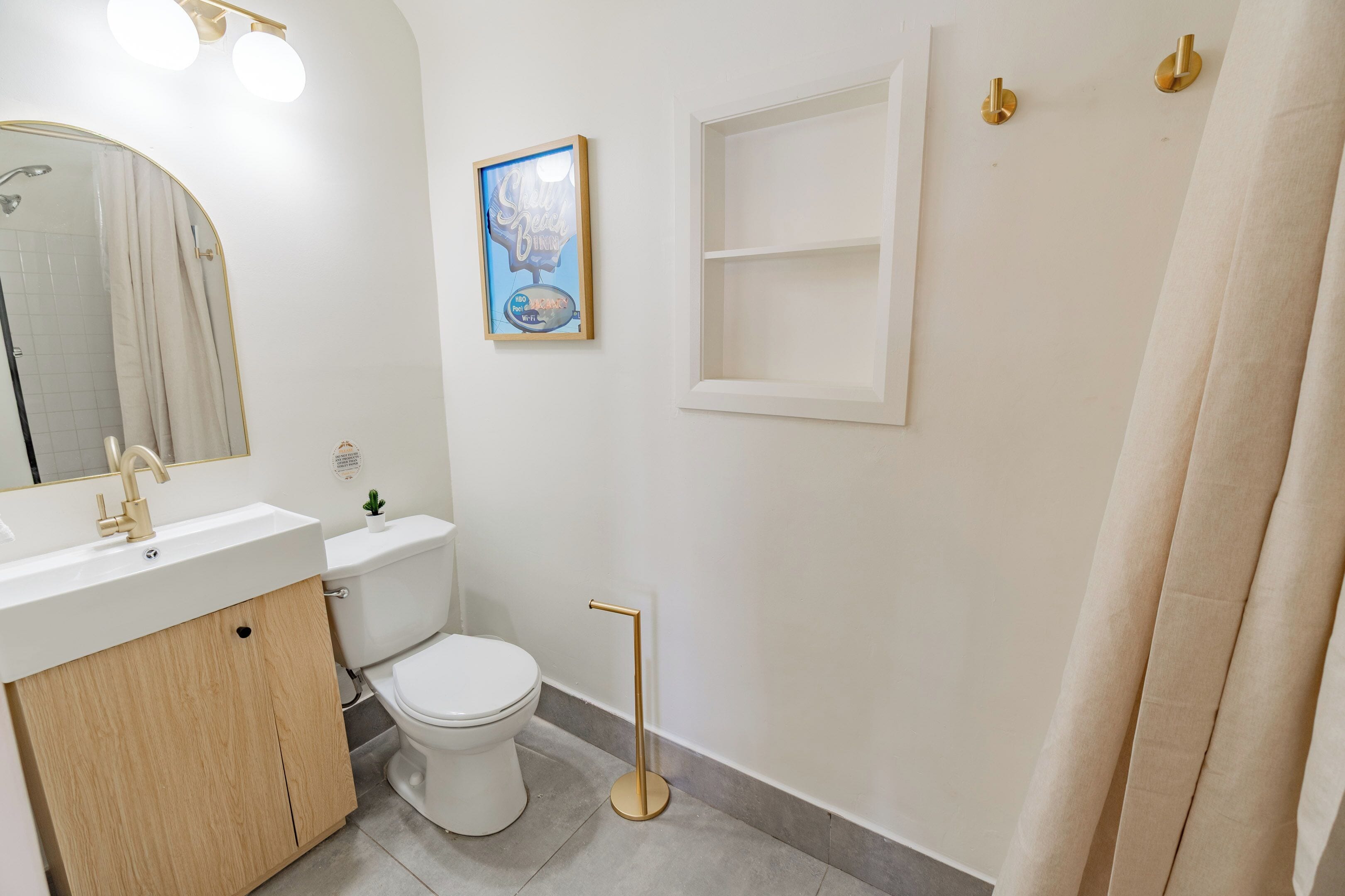 Un baño con lavamanos blanco, inodoro y un cuadro en la pared.