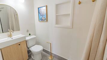 Un baño con lavamanos blanco, inodoro y un cuadro en la pared.