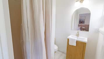 A bathroom with a shower curtain, a sink with a towel, and a mirror.