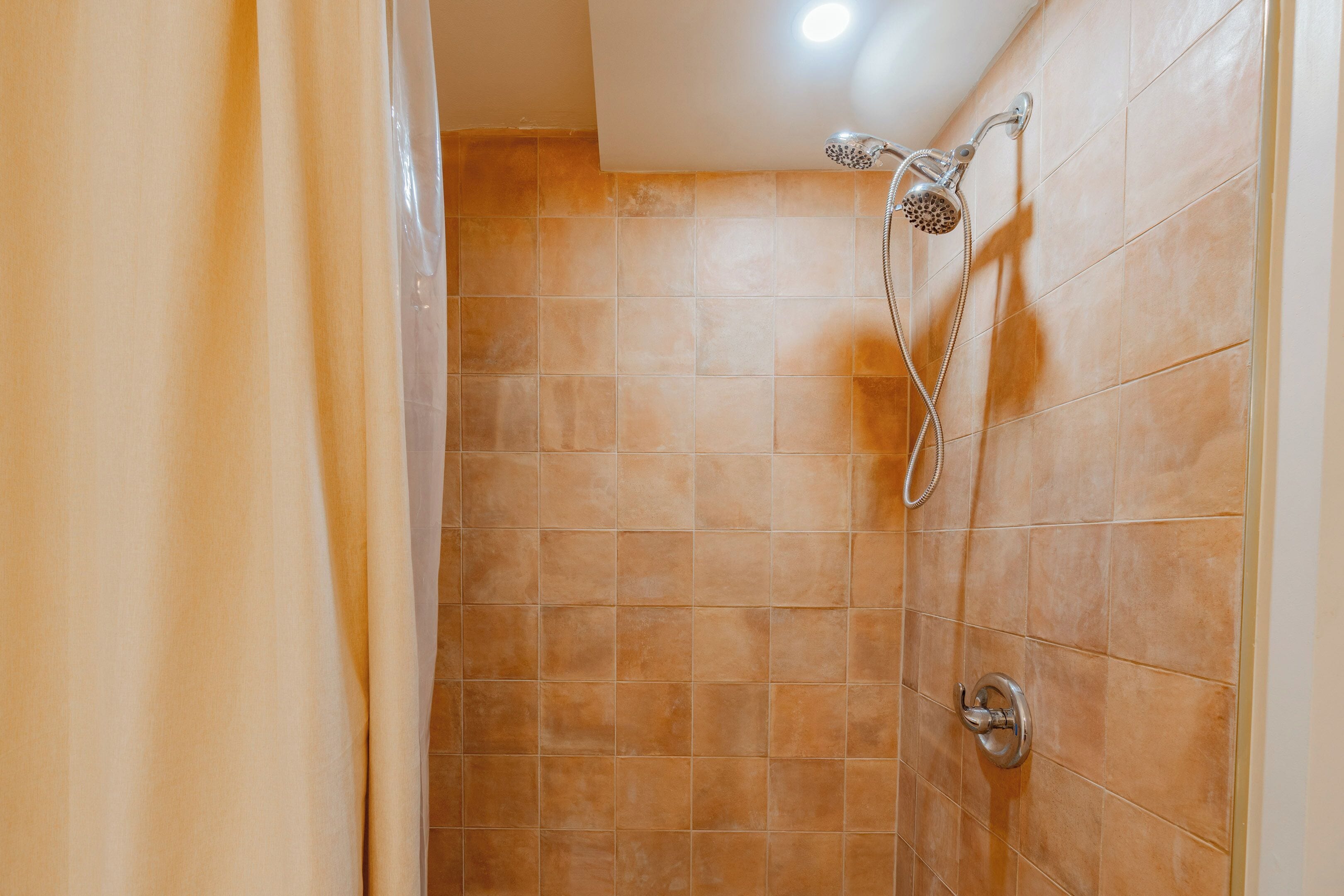 A shower with a handheld showerhead and a wall-mounted faucet.