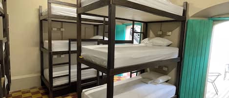 Camas literas en una habitación con piso a cuadros y un ventanal.